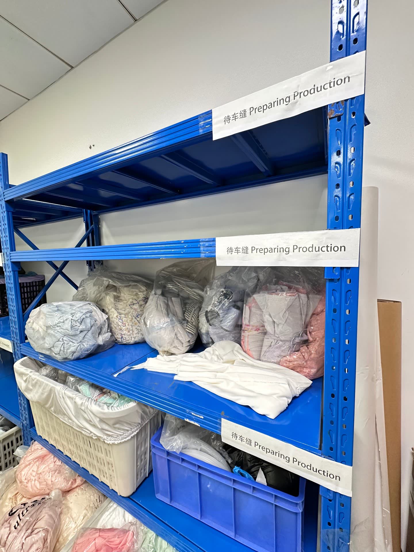 Bilingual labeled shelves preparing production, fabrics sorted per order