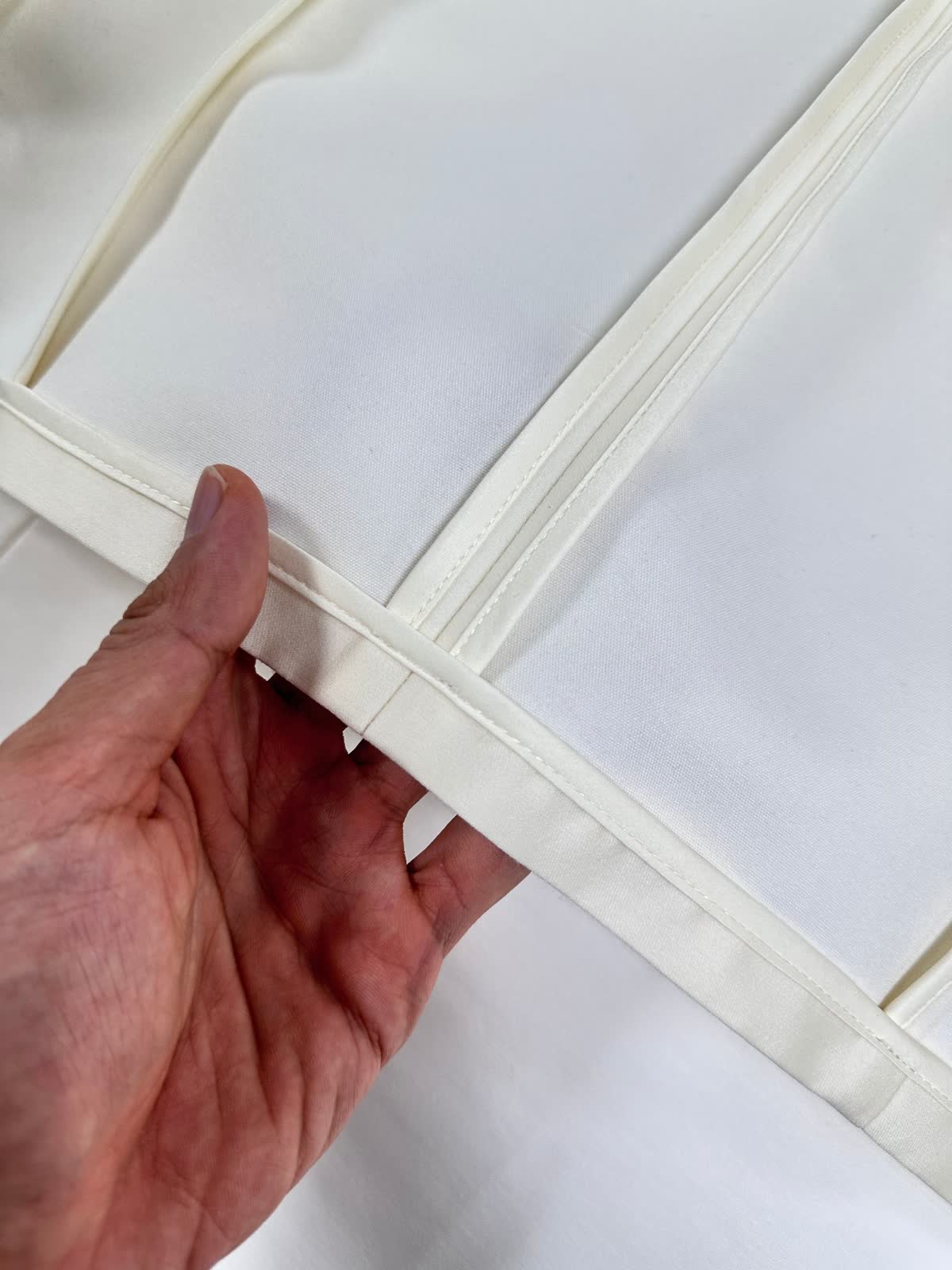 Hidden seam allowances inside an unlined ivory jacket by UP Fashion Guangzhou