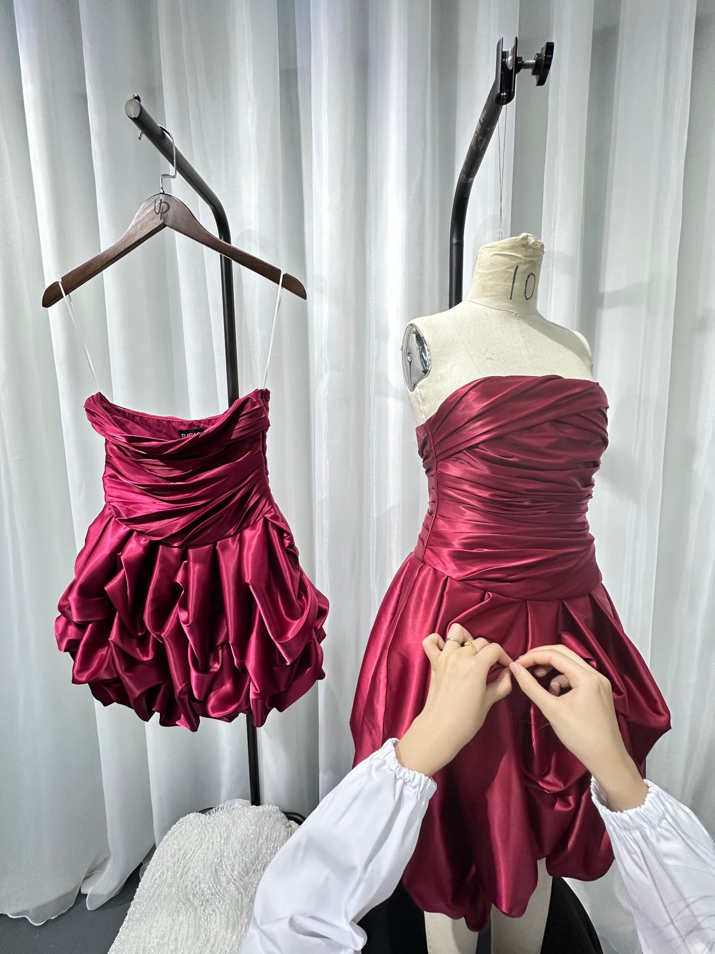 Finished crimson satin dresses on hanger and mannequin